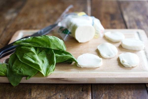 Mozzarella and basil on a cutting board.