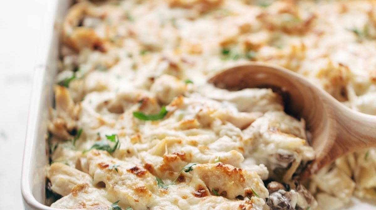 Chicken Tetrazzini baked in a pan with wooden spoon.