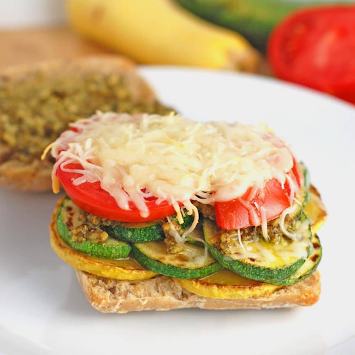 Parmesan and pesto grilled veggie sandwich on a plate.