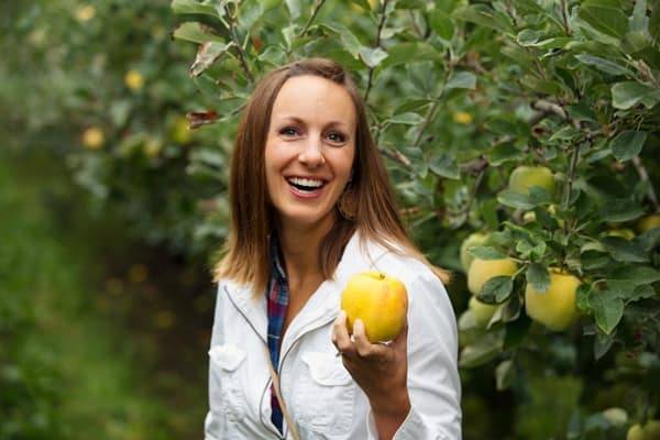 A woman holding up an Opal apple.