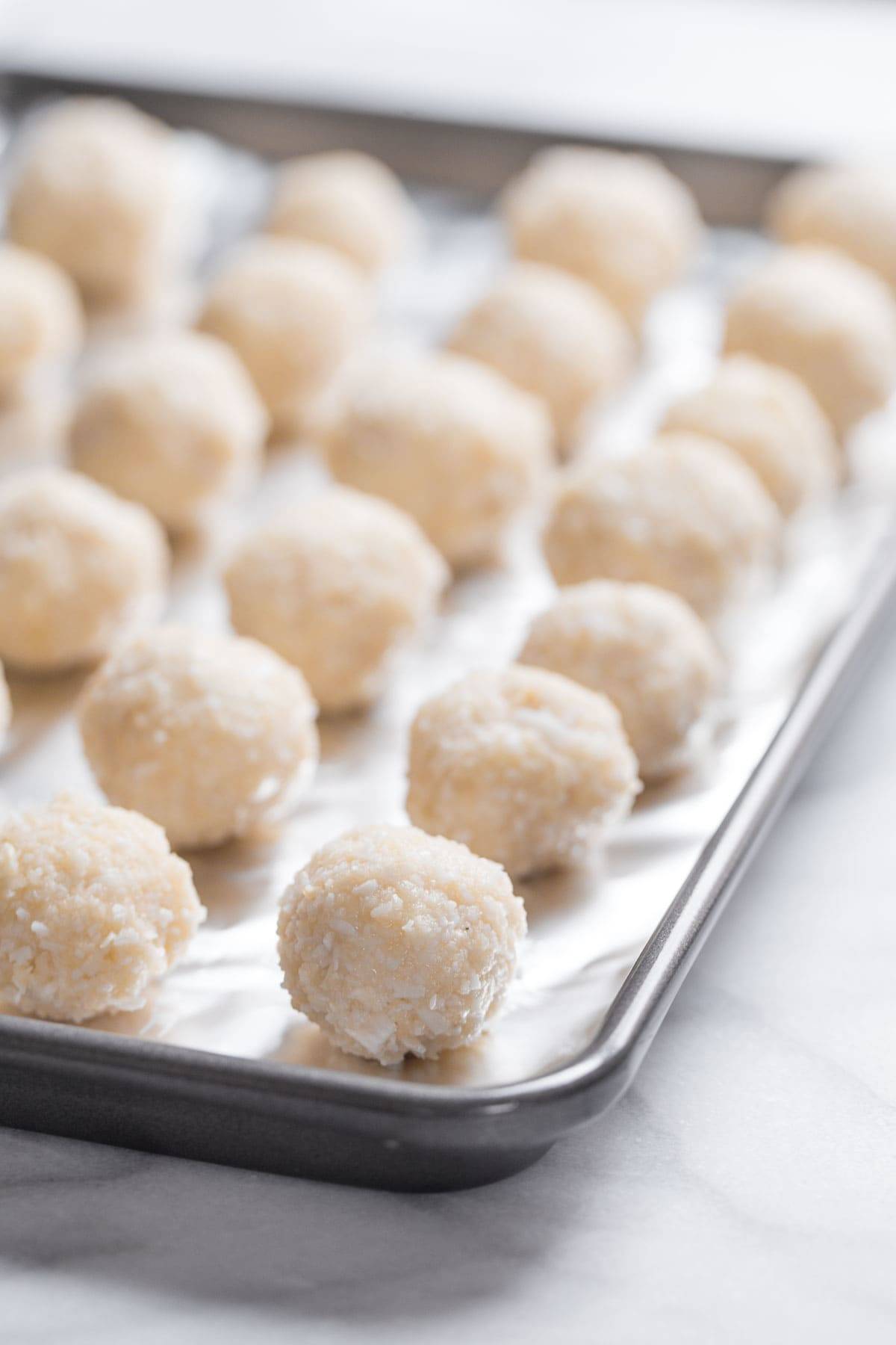 Coconut balls on a sheet pan.