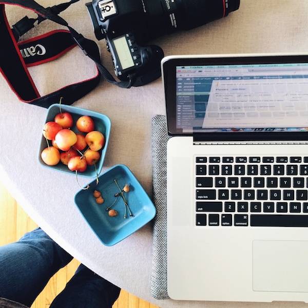 Computer and a blue container of cherries.